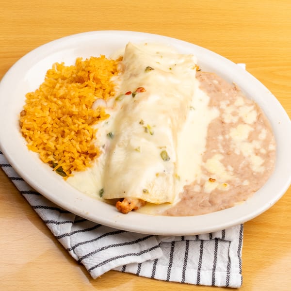 A plate of chicken enchiladas covered in white cheese sauce, with rice and refried beans.
