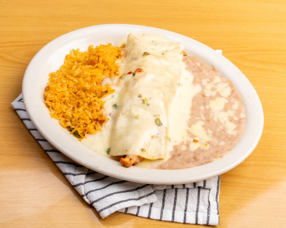 A plate of chicken enchiladas covered in white cheese sauce, with rice and refried beans.