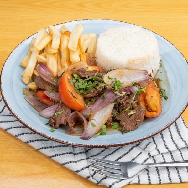 Lomo Saltado with beef, red onions, tomatoes, cilantro, french fries, and white rice.