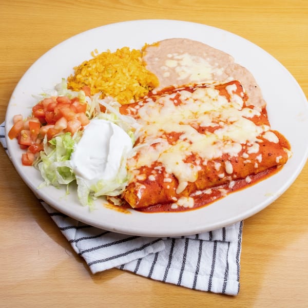 Two cheese enchiladas covered in red sauce and melted cheese, with rice, refried beans, and salad.