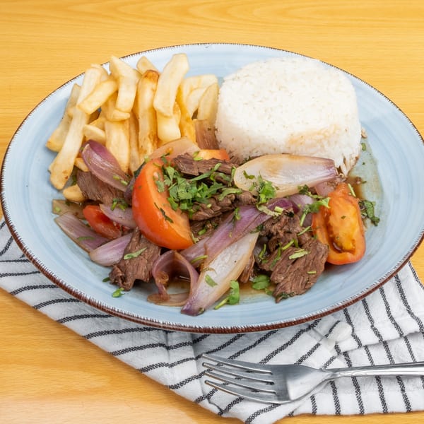 Lomo Saltado with beef, red onions, tomatoes, cilantro, french fries, and white rice.