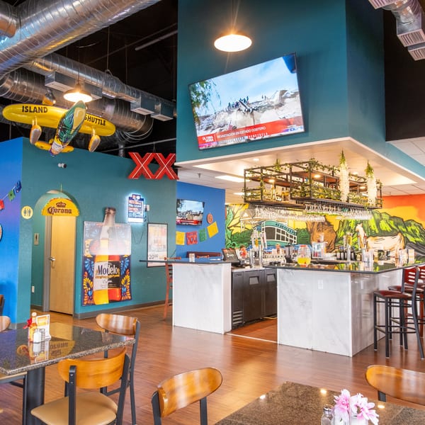A vibrant Mexican restaurant interior with colorful murals, a bar, tables, and decorative elements.