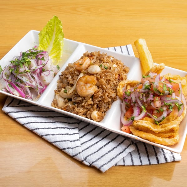 A white rectangular plate with three sections of Peruvian dishes on a wooden table.