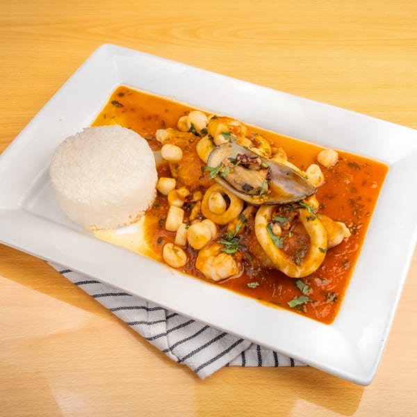 Seafood stew with mussels, squid, shrimp, and scallops in red sauce, served with white rice.